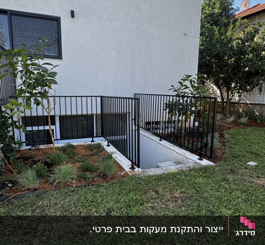מעקה מתכת שחור מותקן סביב ירידה למרתף בחצר בית פרטי